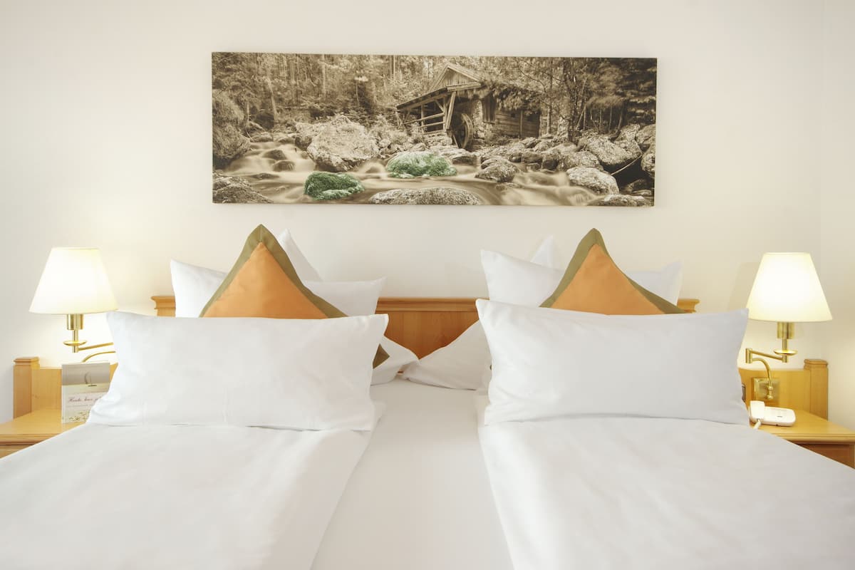 A hotel room with a bed, two nightstands, a wall-mounted painting, and two lamps.