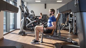A gym with exercise equipment, including a seated row machine and dumbbells.