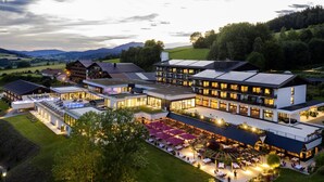 A modern hotel with multiple buildings, outdoor seating areas, and a well-lit courtyard.