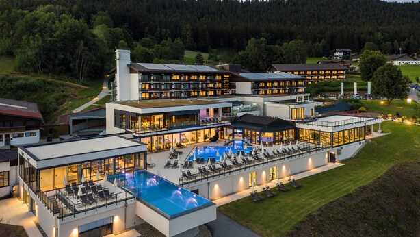 A modern hotel with a rooftop pool, multiple guest rooms, and a well-maintained lawn.