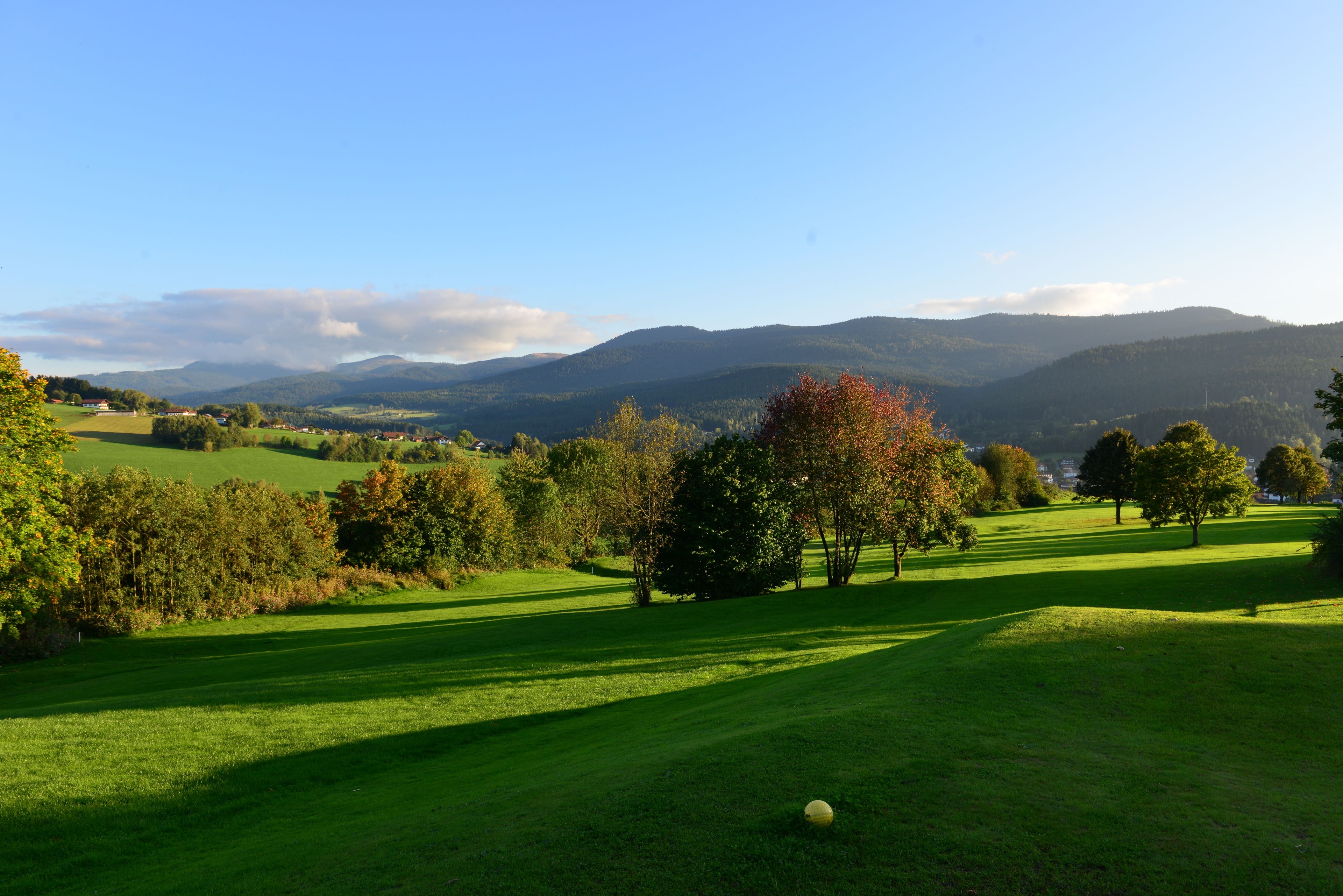 Un campo de golf con vistas despejadas del paisaje circundante, incluyendo colinas y árboles.