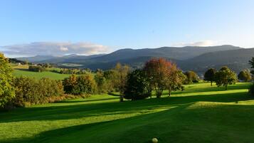 Un campo de golf con vistas despejadas del paisaje circundante, incluyendo colinas y árboles.