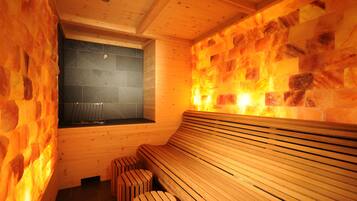 Eine Sauna mit Holzbänken und einer Steinwand.