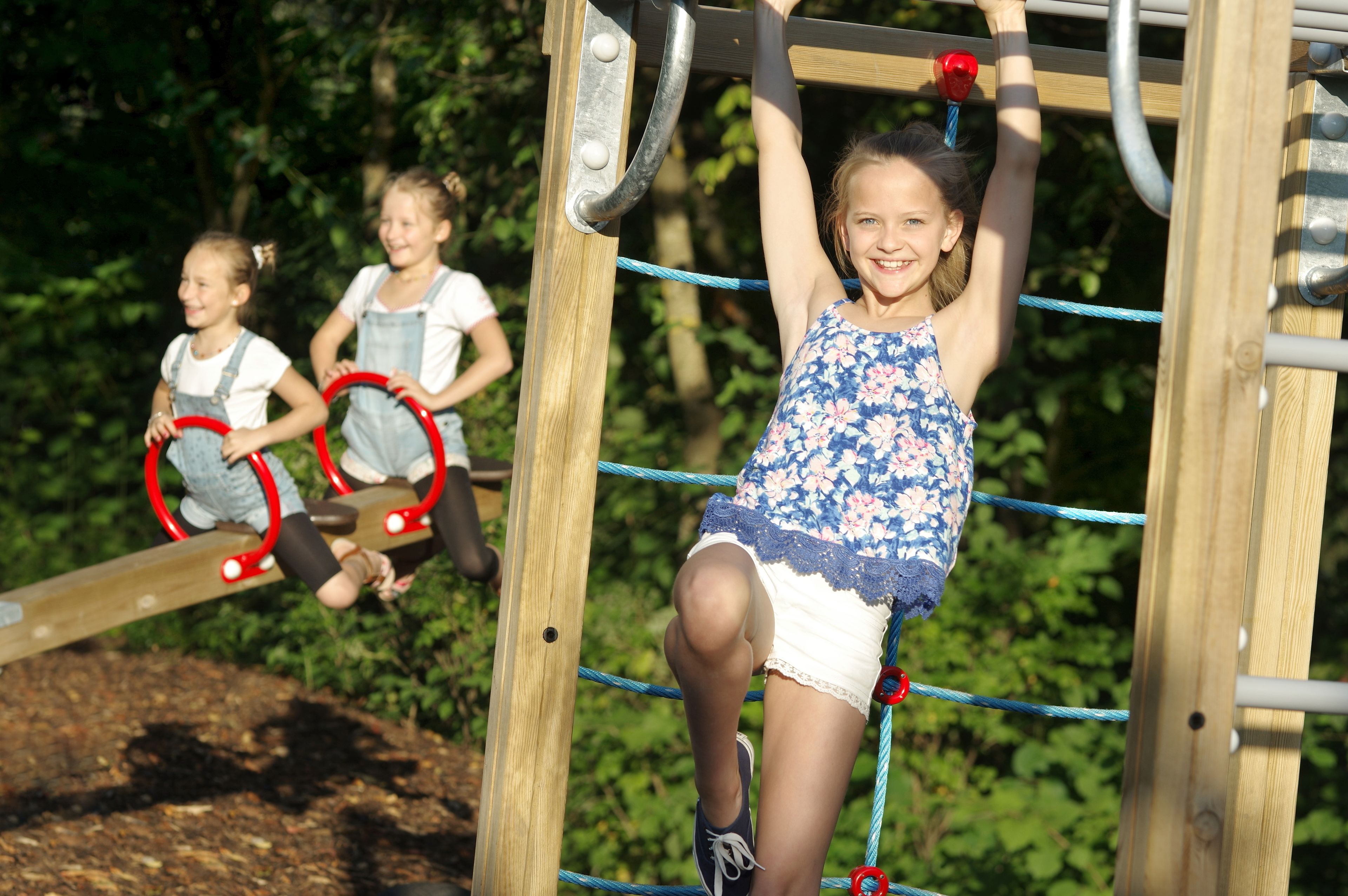 Ein Spielplatz mit einer hölzernen Kletterkonstruktion und einer Wippe.