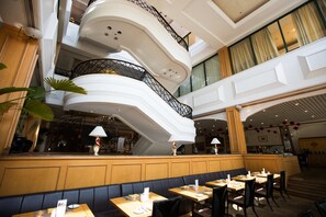 A multi-level hotel lobby with a central staircase, seating areas, and a bar.