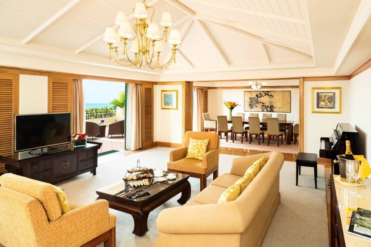 A spacious living room with a television, sofas, a coffee table, and a dining area with chairs and a table.