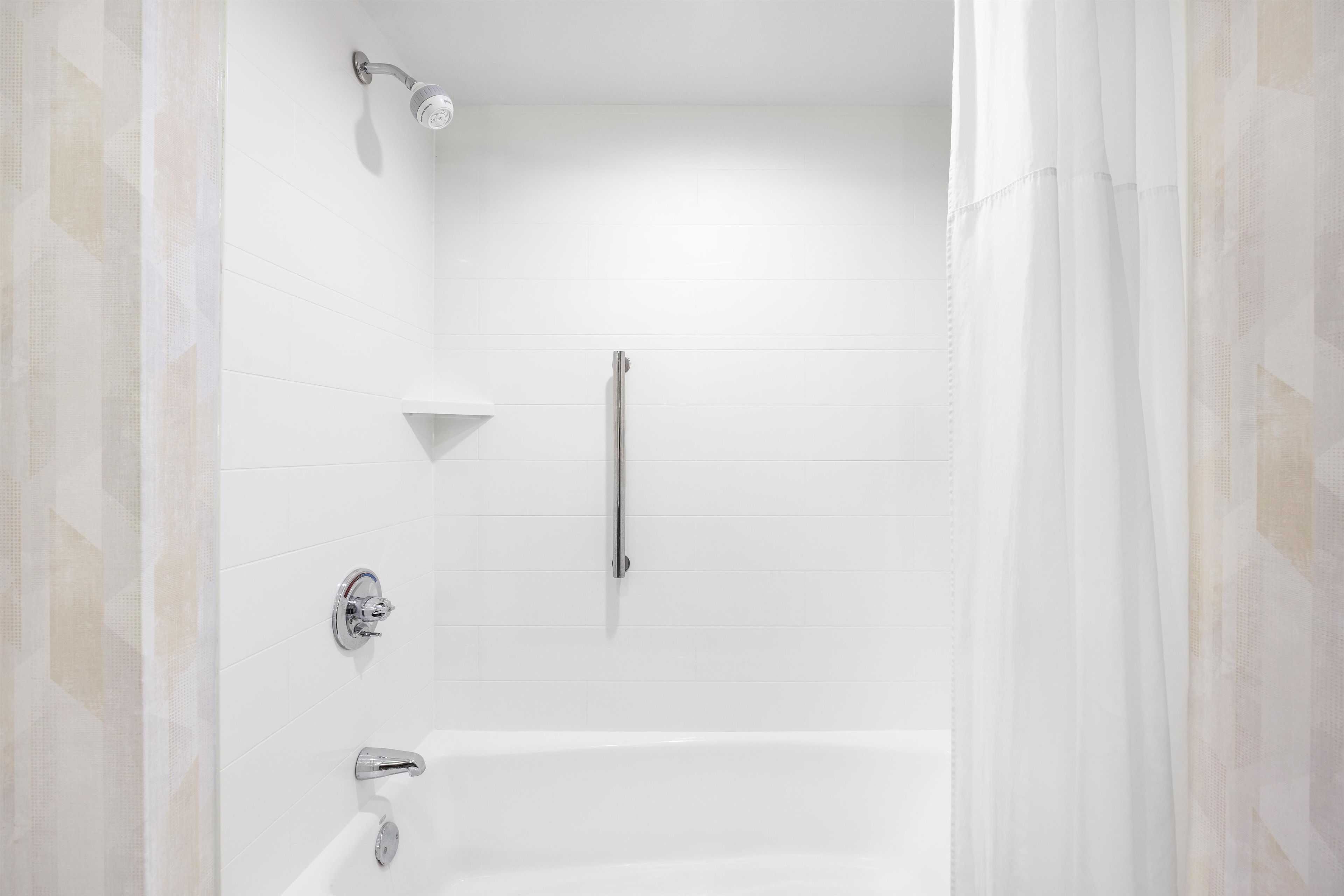 Un baño moderno con bañera, ducha y barra de apoyo.