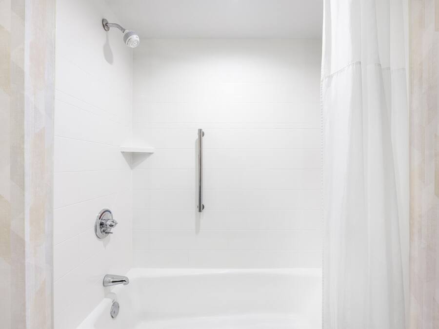Un baño moderno con bañera, ducha y barra de apoyo.