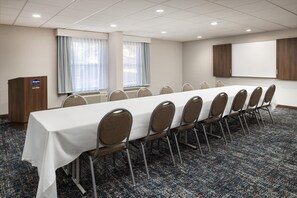 A conference room with a long table, chairs, a podium, and a large screen. - Hampton Inn Oak Ridge Knoxville (Oak Ridge)