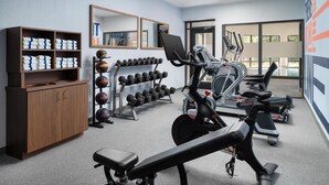 A gym with exercise equipment, a mirrored wall, and a wooden cabinet with towels. - Hampton Inn Oak Ridge Knoxville (Oak Ridge)