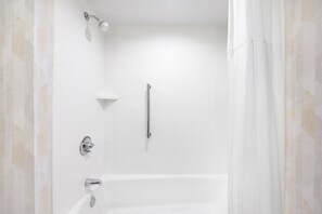 Un baño moderno con bañera, ducha y barra de apoyo.
