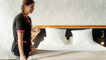 A hotel room with a neatly made bed, a wooden headboard, and a decorative wall panel.