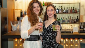 Two people standing at a bar with a variety of bottles in the background.
