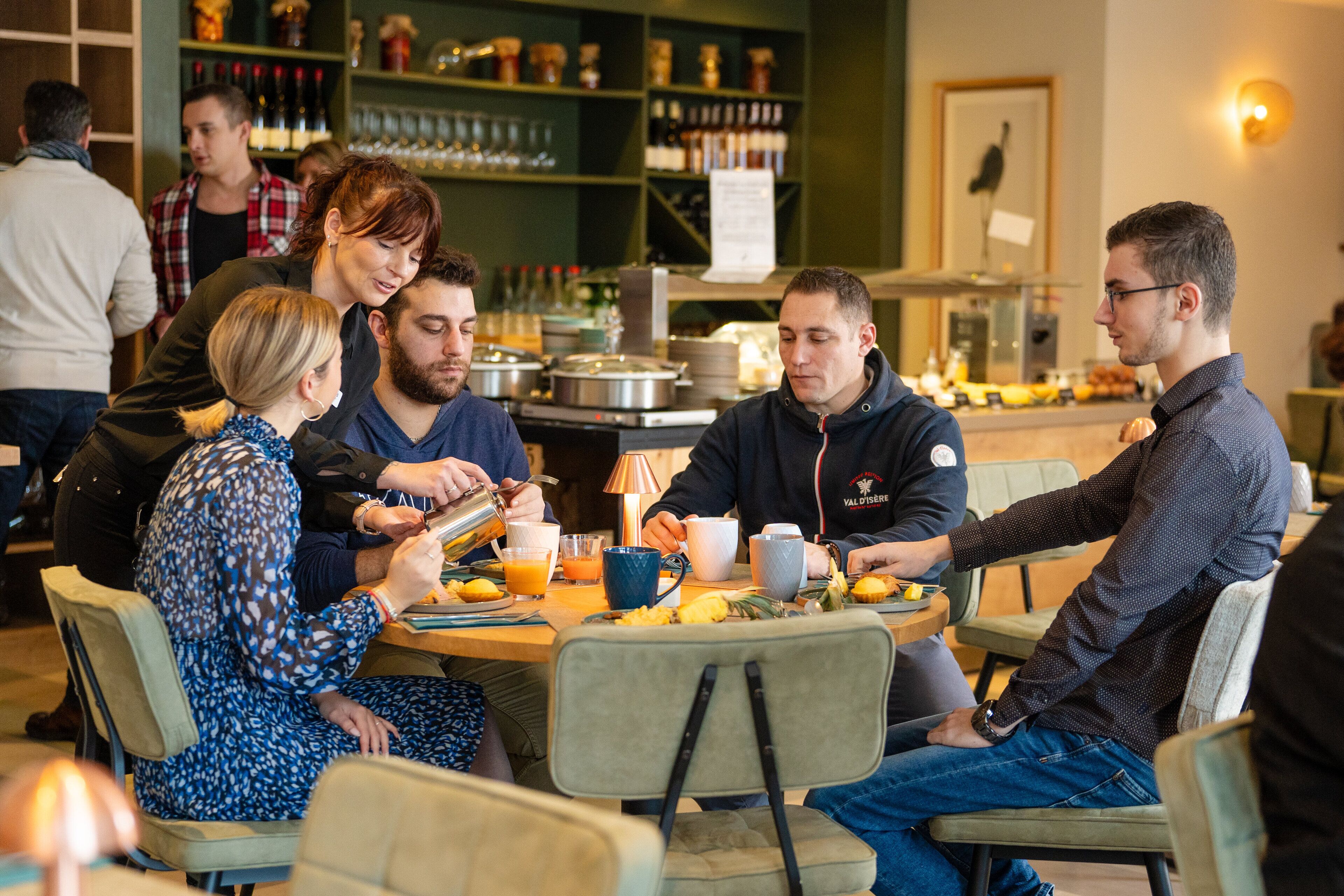 Un grupo de personas sentadas alrededor de una mesa en un restaurante, con un bar al fondo.