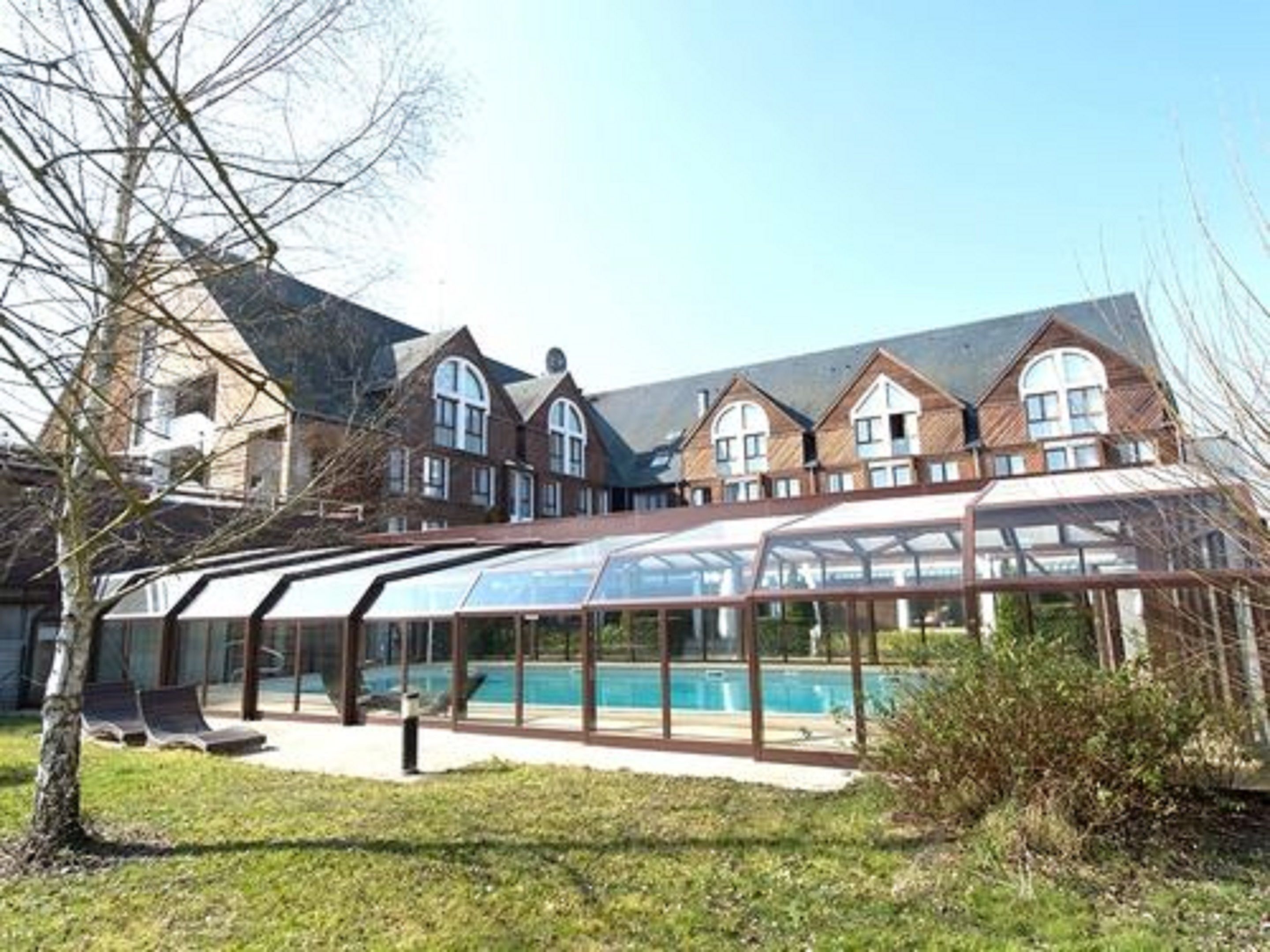 Ein großes Haus mit einem überdachten Pool und einer überdachten Terrasse.