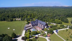 A large, historic building with a prominent central section and a smaller annex. - Domaine de la Forêt d’Orient, Logis Hôtel, Restaurant, Spa & Golf (Rouilly-Sacey)
