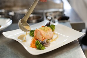 A white plate with a piece of salmon, broccoli, and carrots. - Domaine de la Forêt d’Orient, Logis Hôtel, Restaurant, Spa & Golf (Rouilly-Sacey)