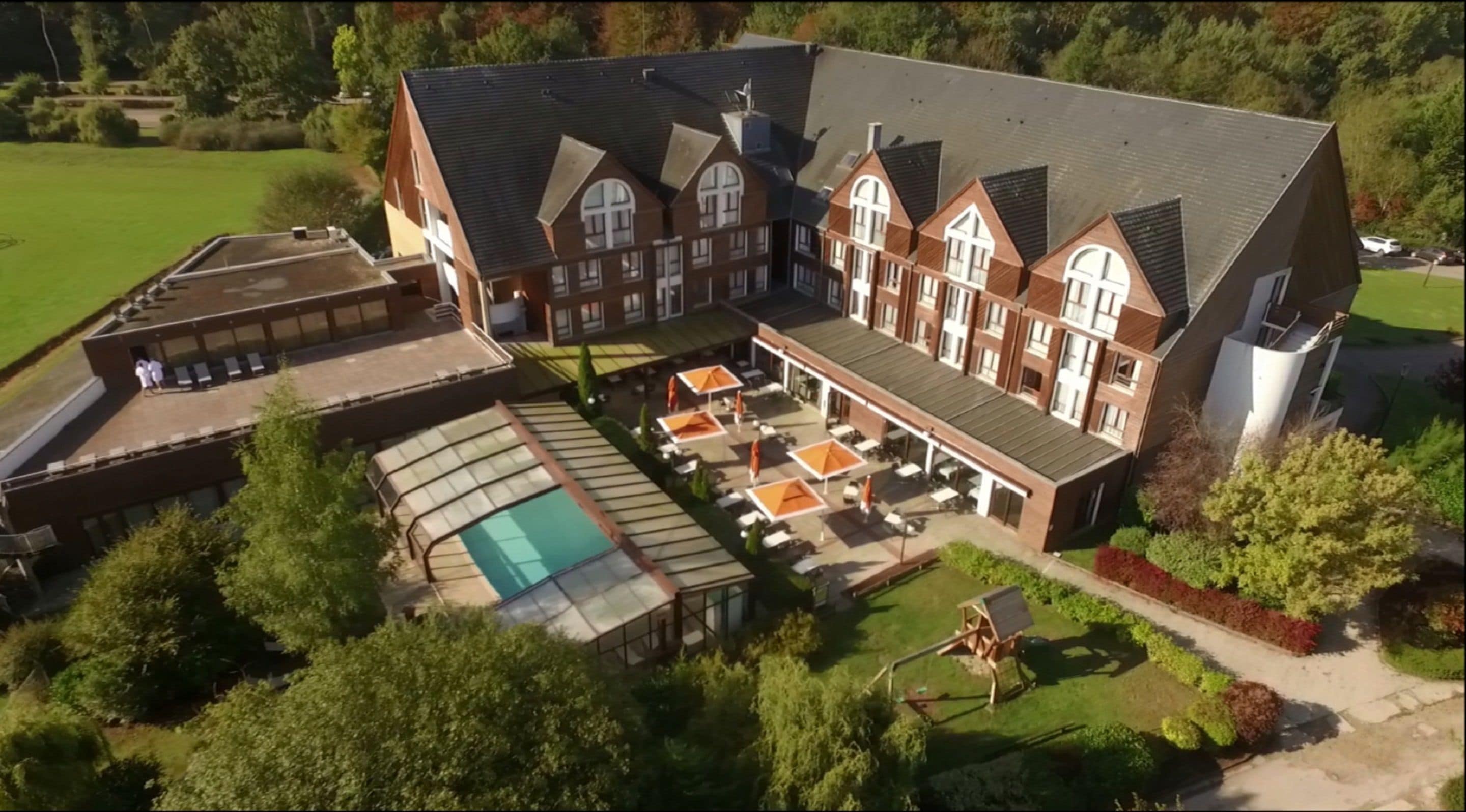 A large building with a swimming pool, outdoor seating, and a covered patio area.