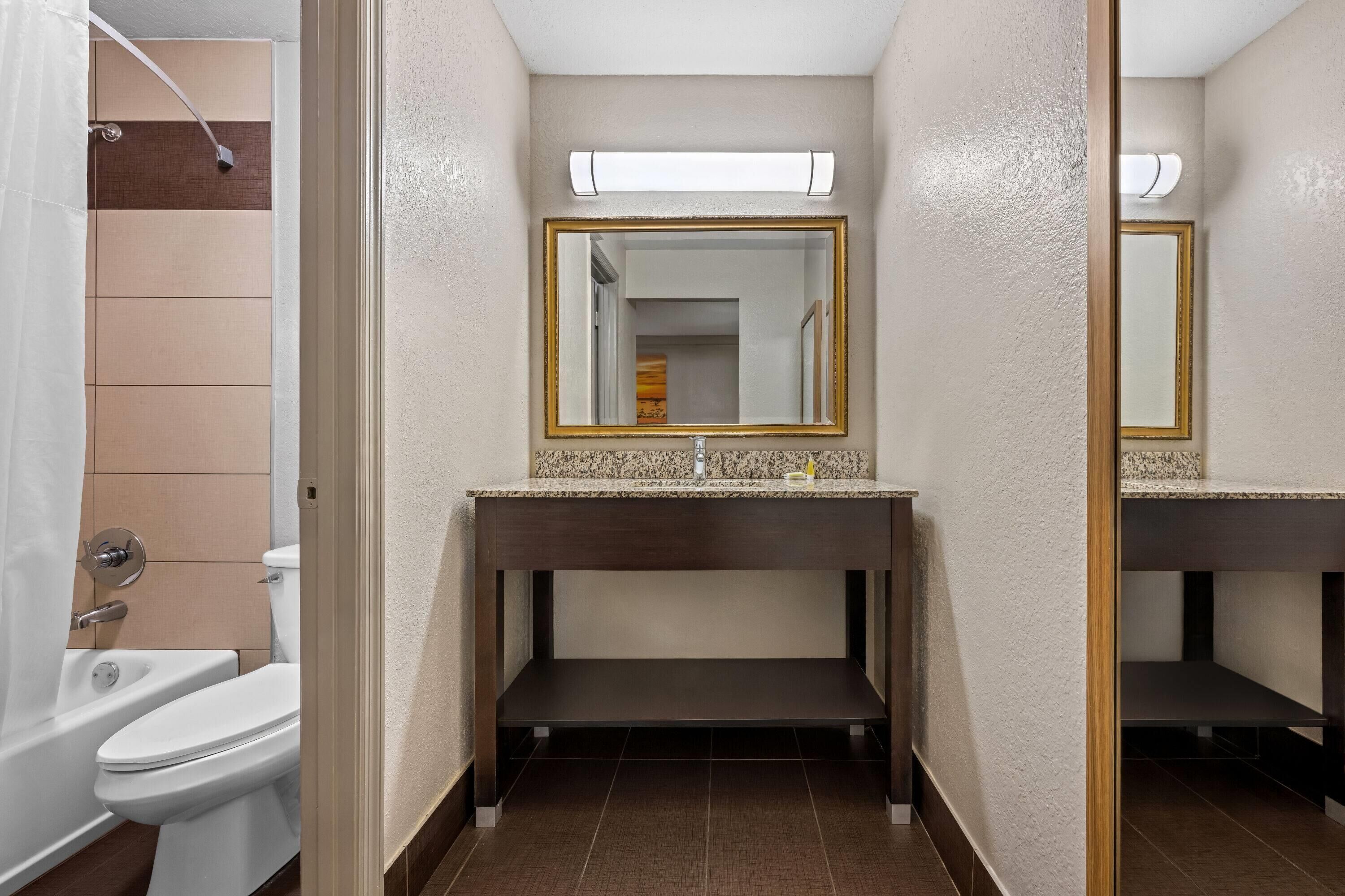 A bathroom with a toilet, sink, and mirror.