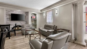 A modern living room with a flat-screen TV, leather sofas, a glass coffee table, and a dining area with chairs. - Days Inn by Wyndham Birmingham/West (Birmingham)