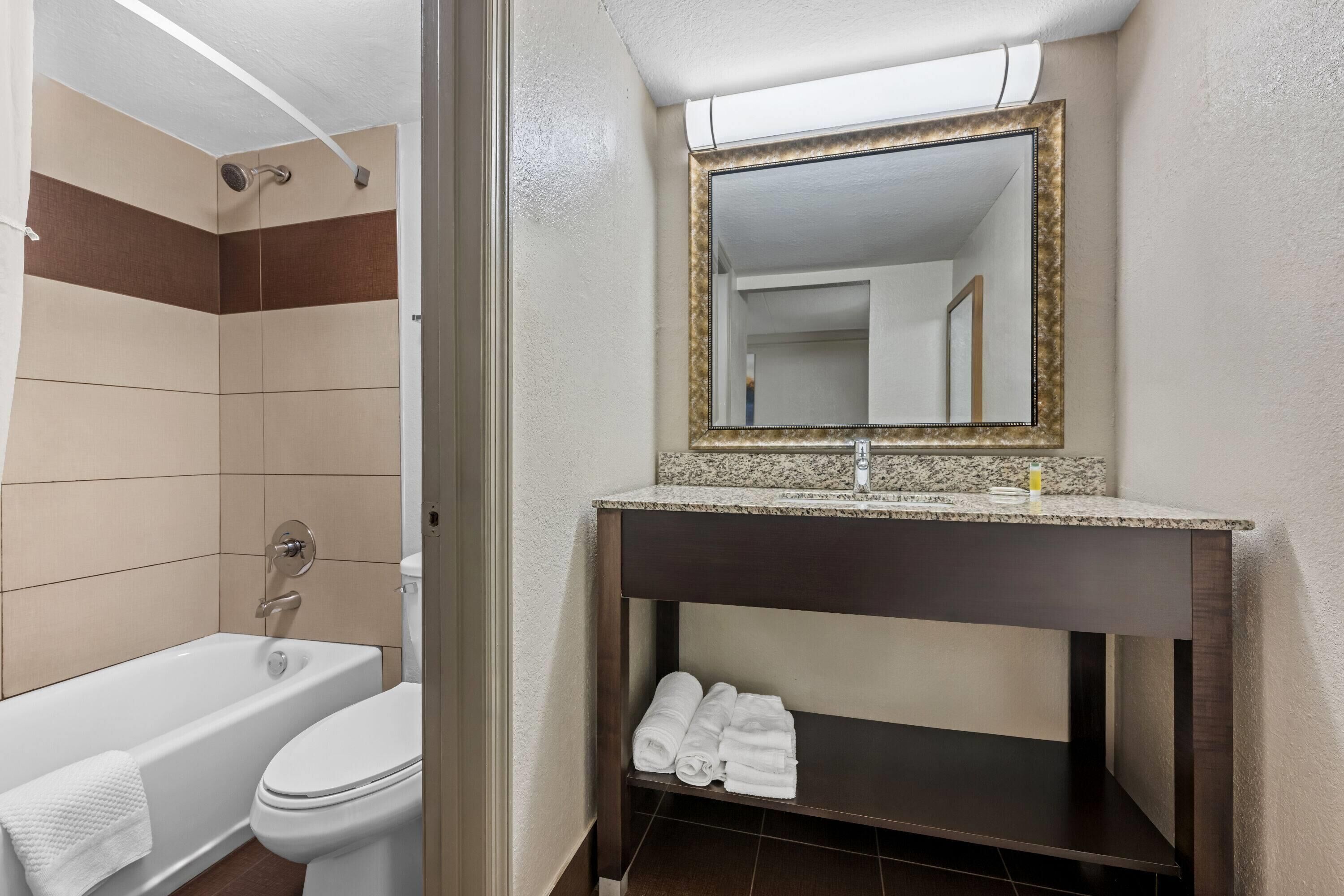 A bathroom with a bathtub, toilet, and a vanity with a mirror.