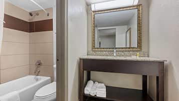 Un baño con bañera, inodoro y tocador con espejo.