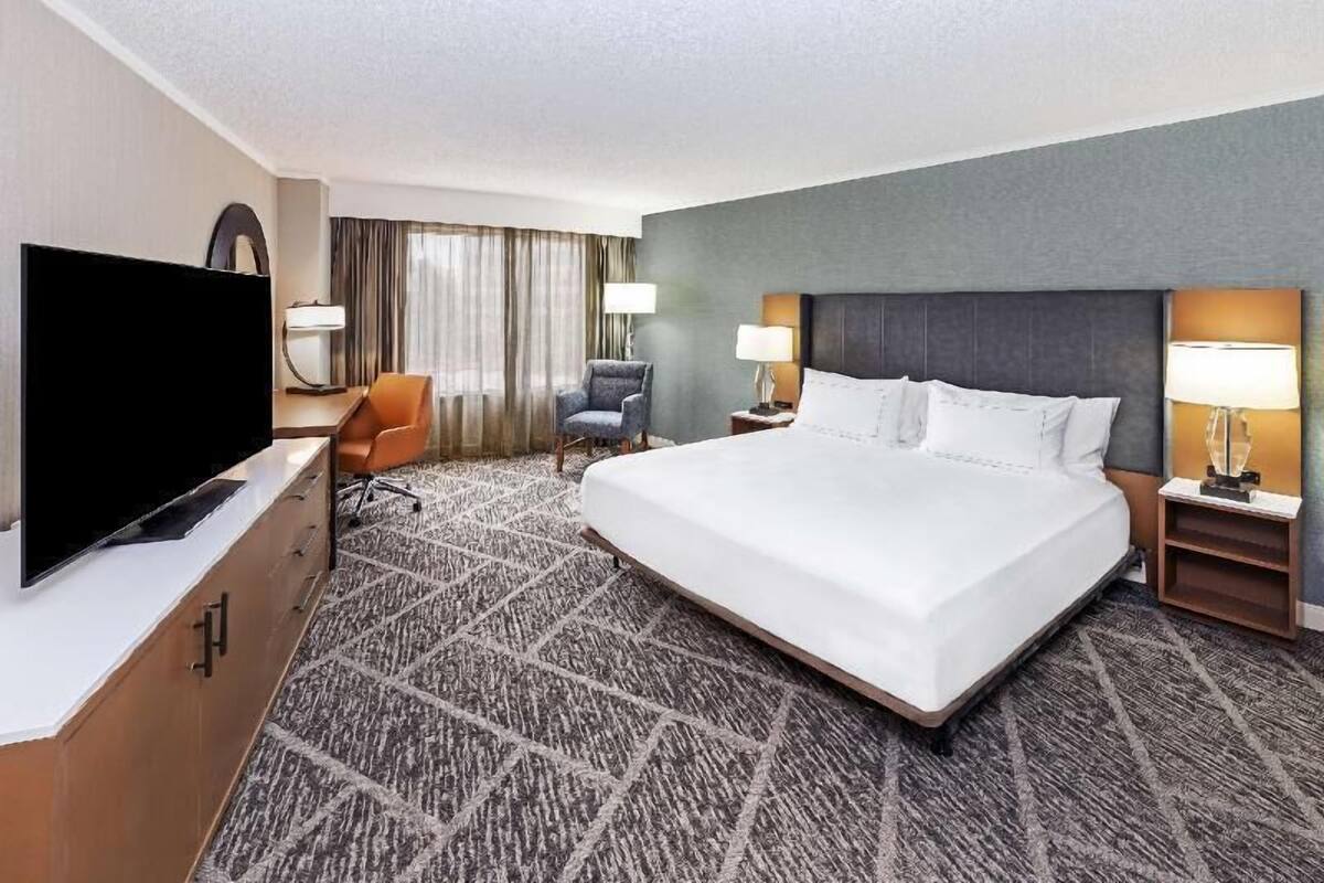 A hotel room with a large bed, a television, a desk, and a chair.