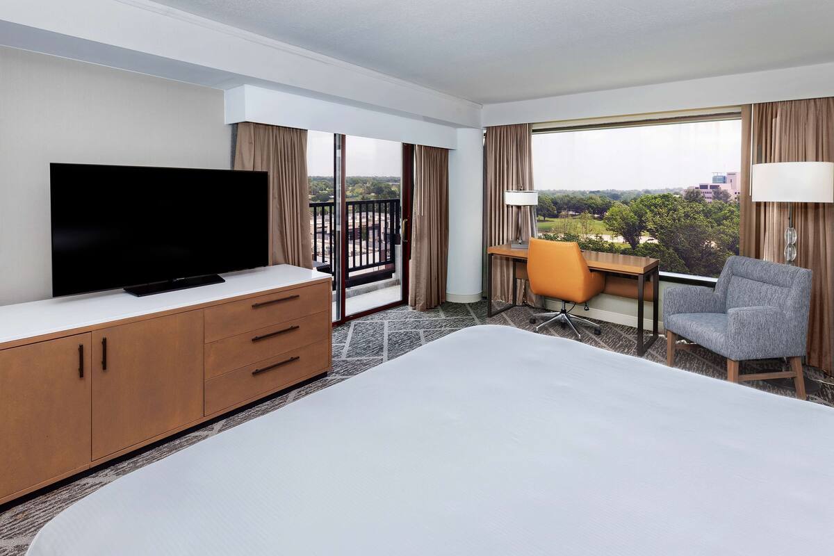 A hotel room with a bed, a TV, a desk, and a chair.