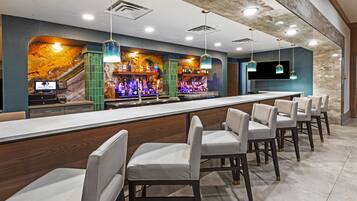 A bar area with a long counter, multiple seating options, and a variety of bottles and glasses.