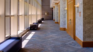 A hotel corridor with a patterned carpet, large windows, and a modern design. - DoubleTree by Hilton Tulsa - Warren Place (Tulsa)