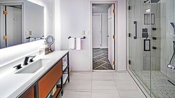 Een moderne badkamer met een grote spiegel, een witte wastafel en een douche met glazen wanden.