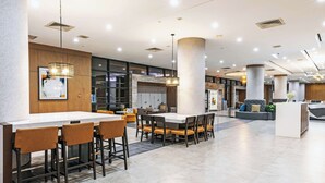 A spacious lobby with a central bar area, seating arrangements, and a reception desk. - DoubleTree by Hilton Tulsa - Warren Place (Tulsa)