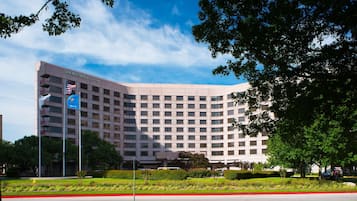 A large, multi-story hotel with a curved facade and a flagpole with an American flag.