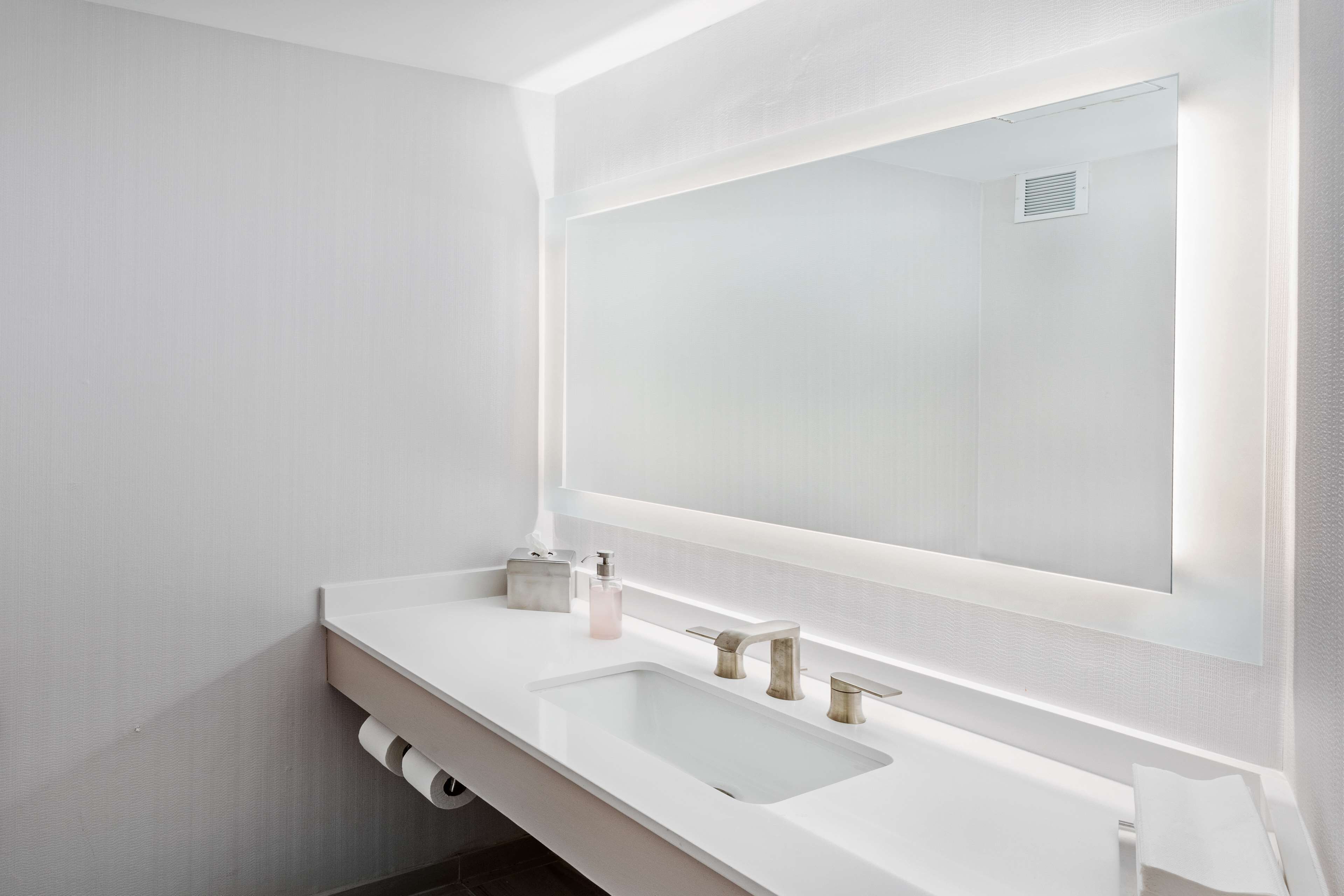 Un baño moderno con un espejo grande, dos lavamanos y un inodoro.