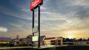 A Red Roof Inn with a prominent sign, a parking lot, and a building with a red roof and entrance.