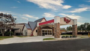 A Red Roof Inn with a modern architectural design, featuring a prominent entrance and a covered parking area. - Red Roof Inn Lumberton (Lumberton)