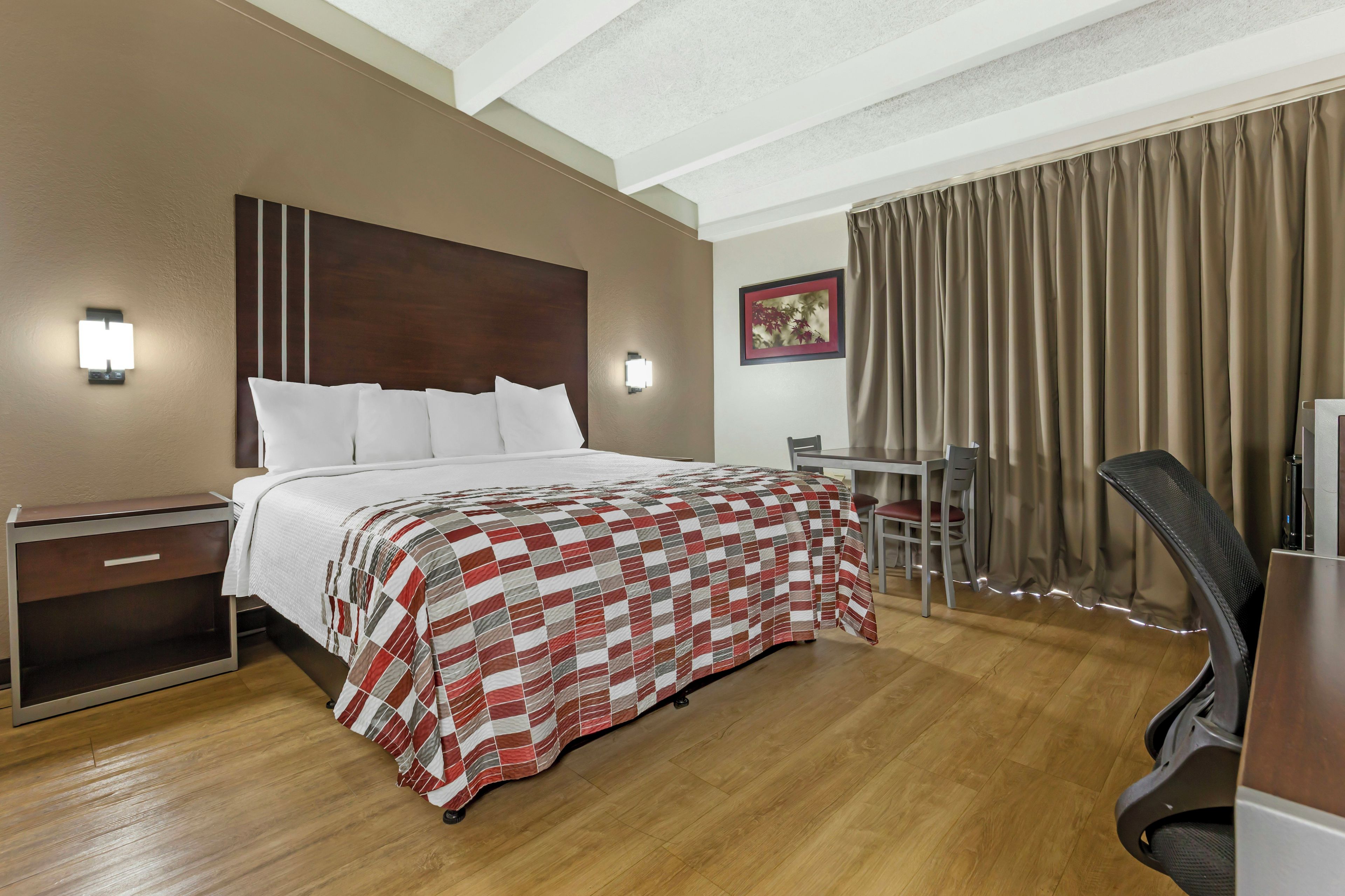 A hotel room with a large bed, bedside tables, a desk, and a chair.