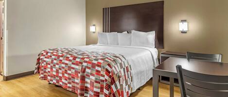 A hotel room with a bed, a desk, and a chair.