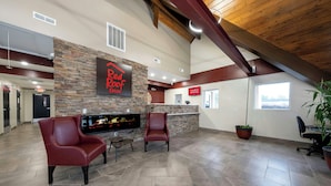 A spacious lobby with a stone accent wall, a fireplace, leather chairs, and a large window.