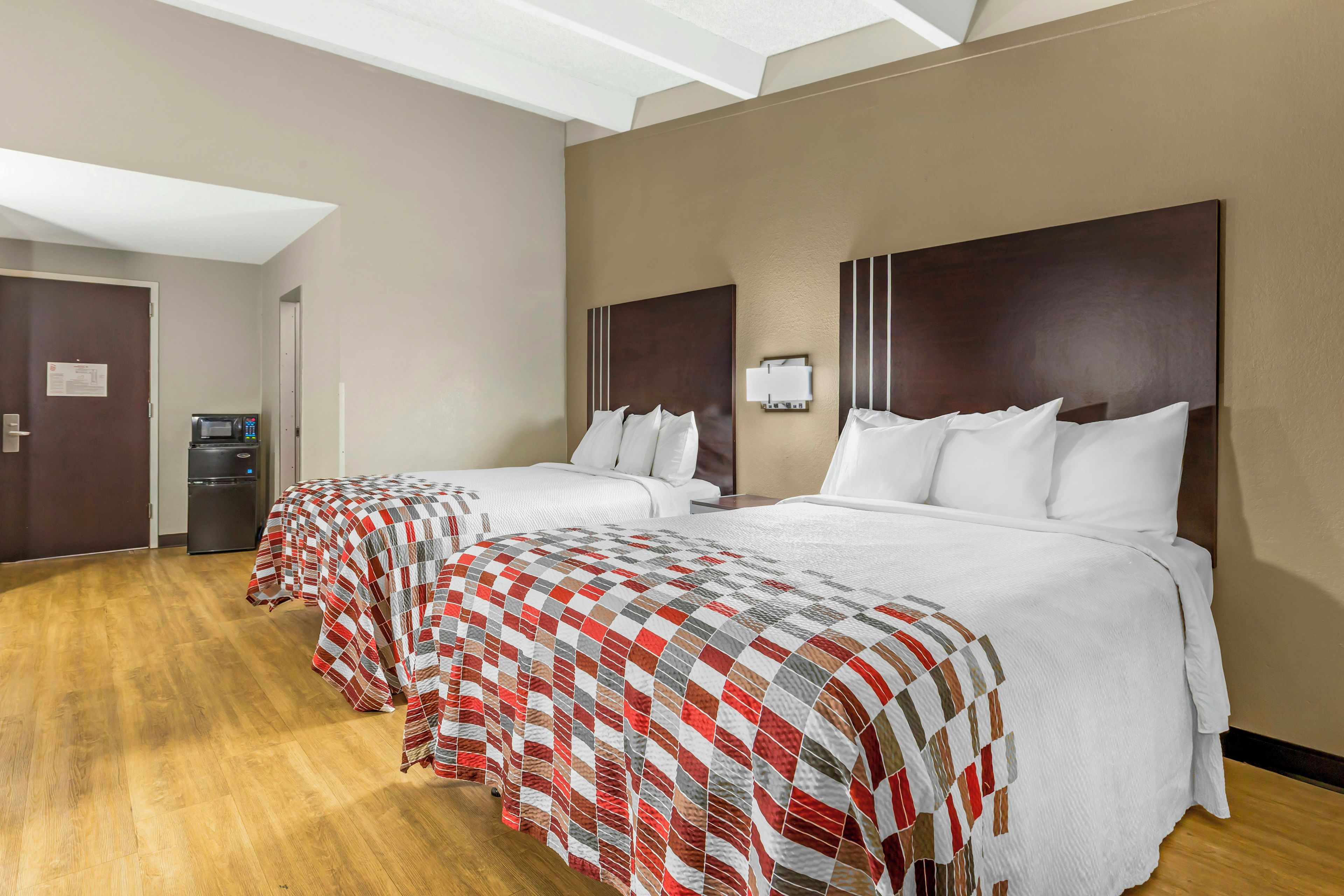 A hotel room with two beds, a microwave, and a small refrigerator.