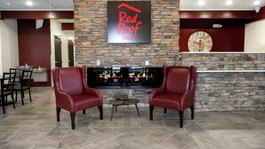 A Red Roof Inn lobby with stone walls, a fireplace, leather chairs, and a flat-screen TV. - Red Roof Inn Lumberton (Lumberton)