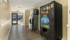 A hallway with a vending machine, a refrigerator, and an exit door.
