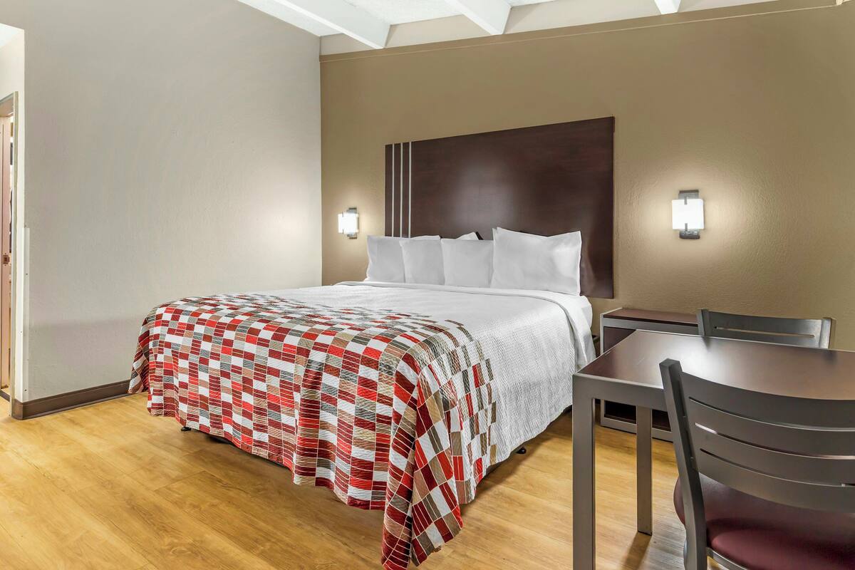 Une chambre d’hôtel avec un lit, un bureau et une chaise.
