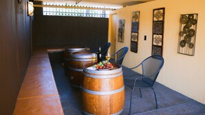 A wine cellar with wooden barrels, a table with a fruit bowl, and a chair.