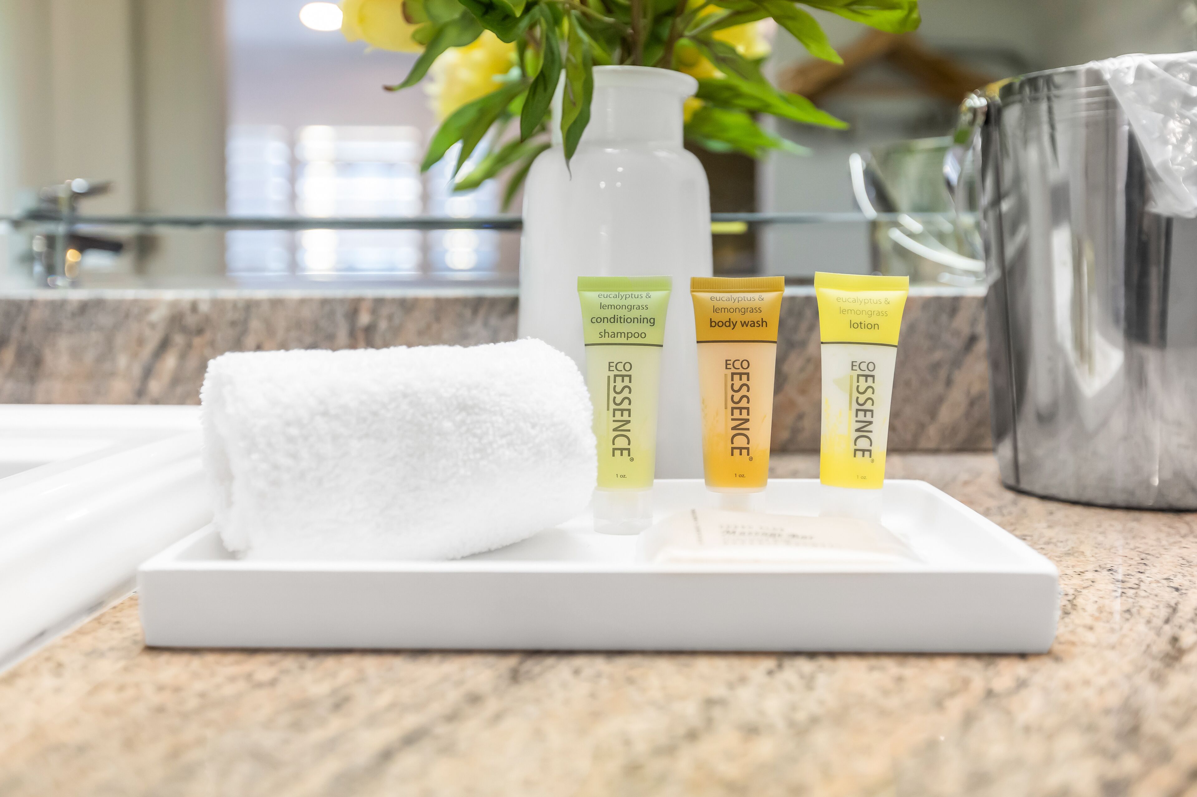 Un meuble-lavabo de salle de bain avec une serviette blanche, un flacon de shampoing-après-shampoing aux huiles d’eucalyptus et de citronnelle, un gel douche et une lotion.