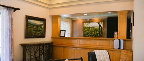 A room with a wooden bench, a framed painting, and a window with curtains.