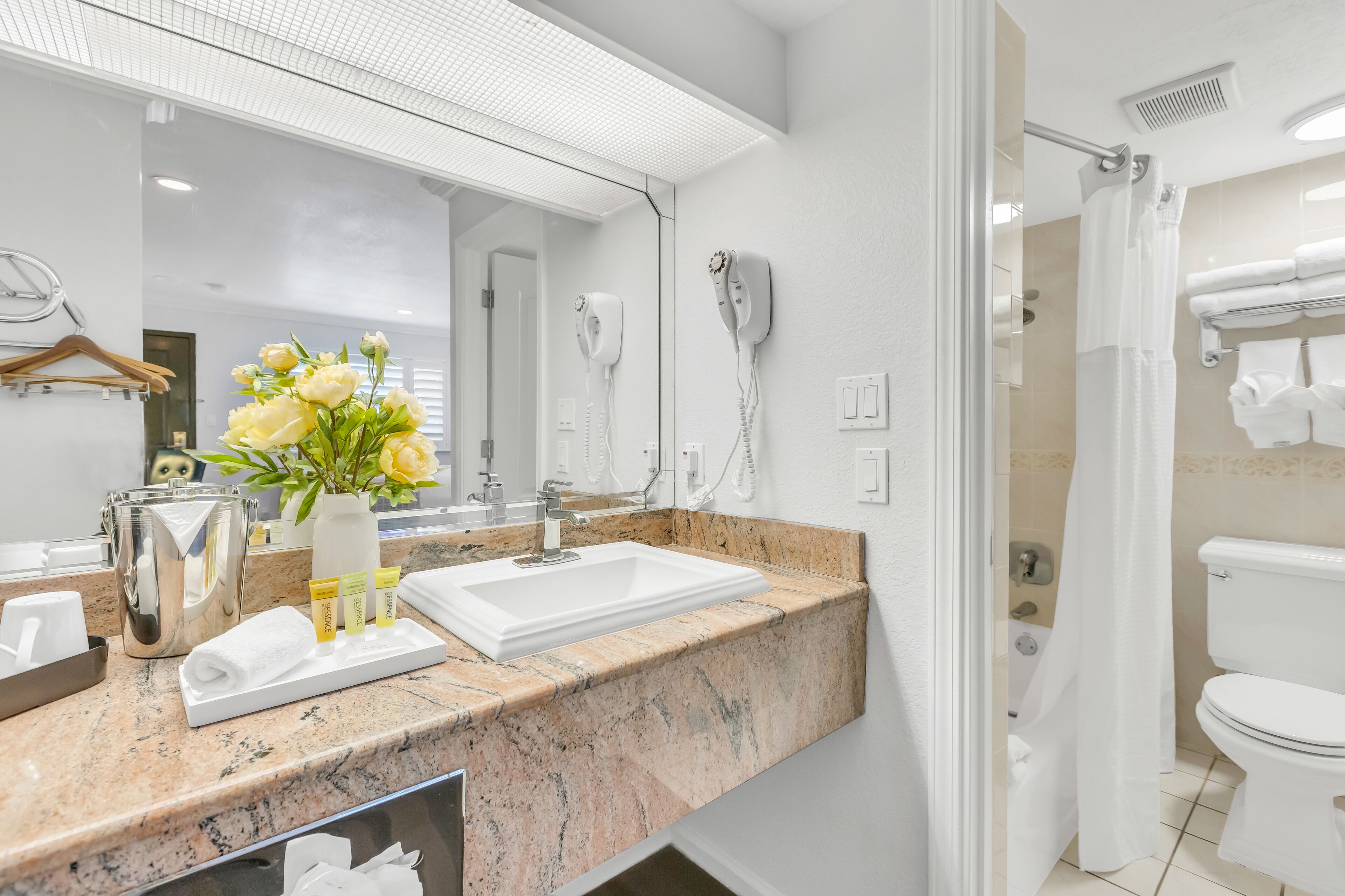 A modern bathroom with a marble countertop, a white sink, a hairdryer, and a shower curtain.