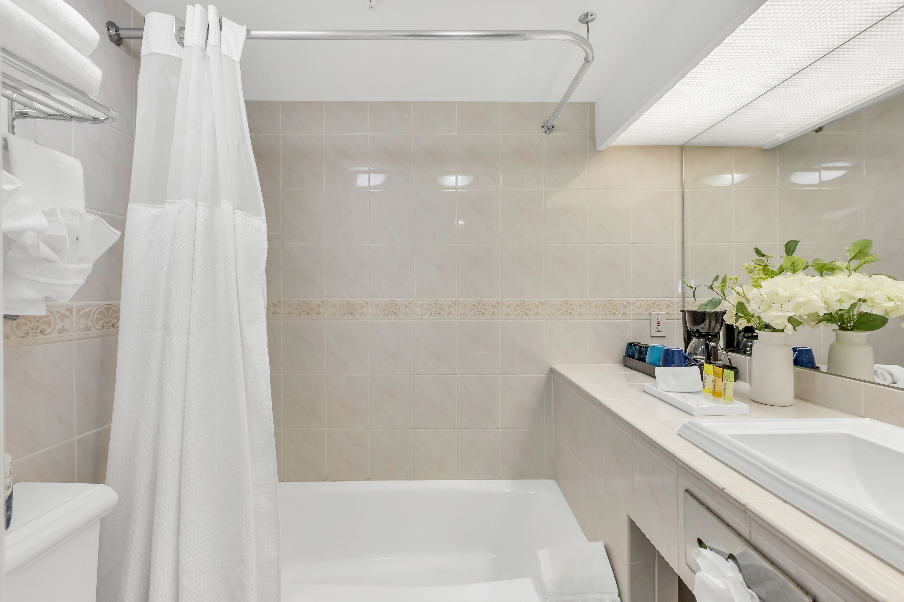 Une salle de bain moderne avec une baignoire, une douche avec un rideau blanc, un meuble-lavabo avec un miroir et un évier.