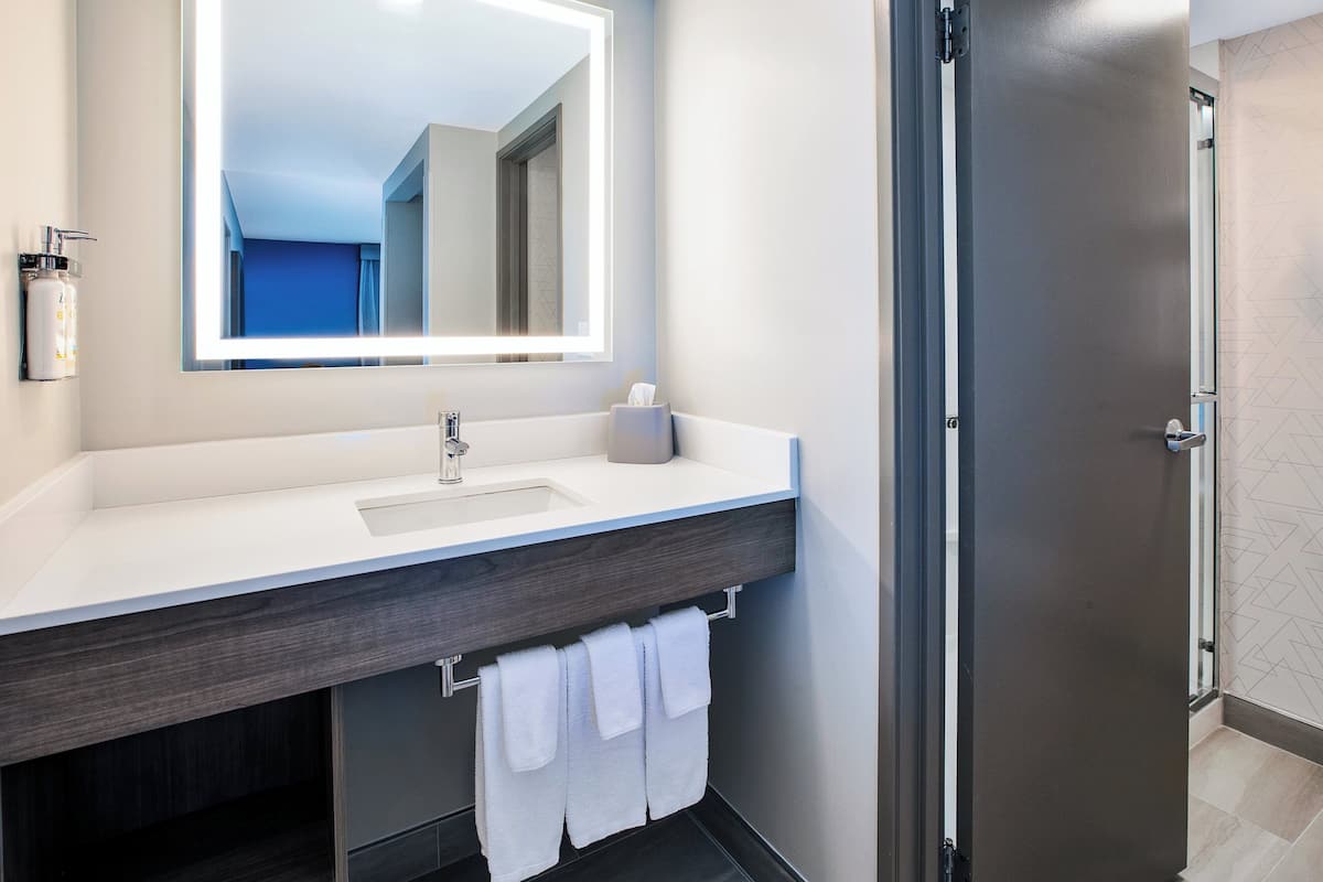 A modern bathroom with a large mirror, a sink, and a towel rack.