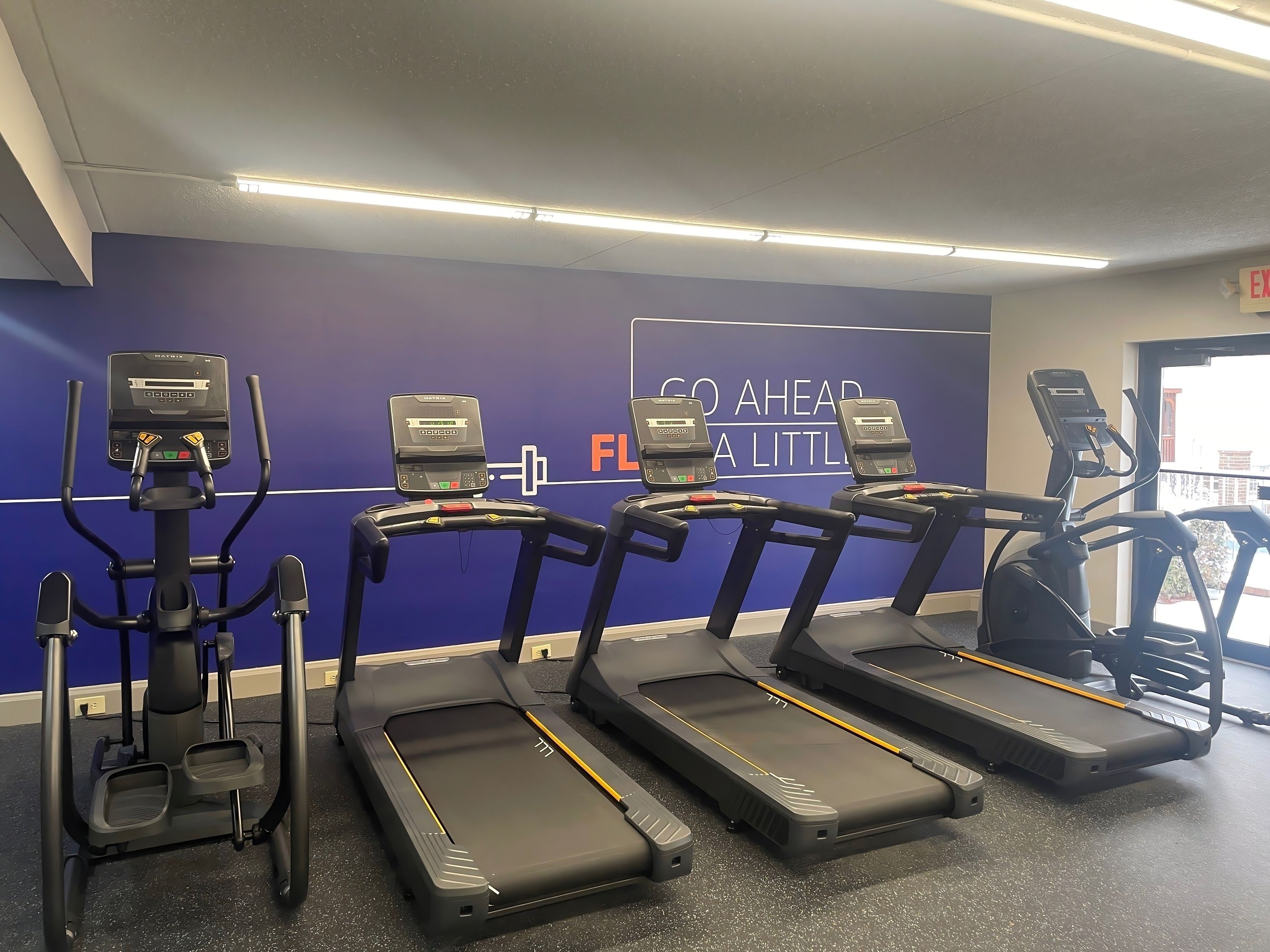 Una palestra con tapis roulant, cyclette e scaletta allenamento.